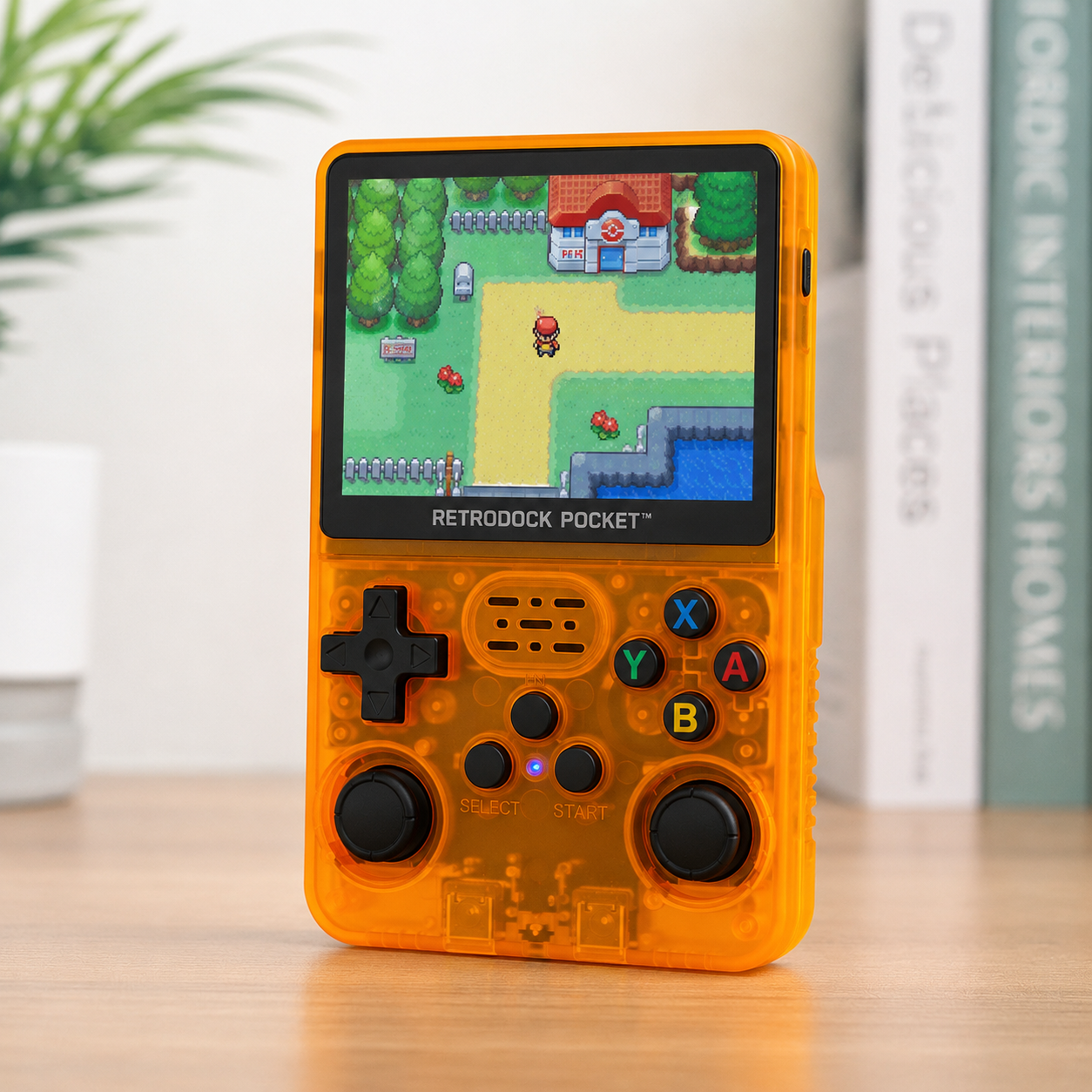 Orange handheld gaming console with screen displaying a game on a wooden surface.